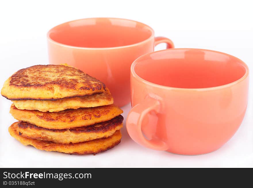 Fresh homemade pumpkin pancakes and two orange cups for breakfast isolated on white background