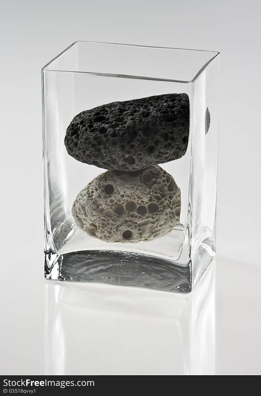 Two stones in a glass container on white background