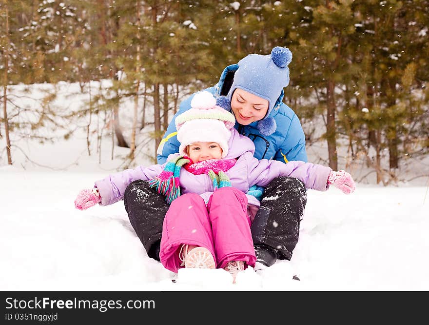 Happy family; young mother and her daughter having fun in the winter park (focus on the child). Happy family; young mother and her daughter having fun in the winter park (focus on the child)