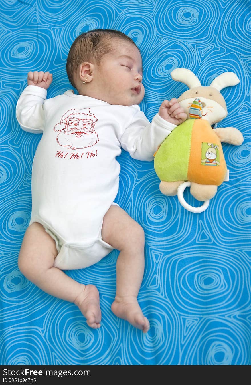 Baby girl of 21 days old sleeping on blue background. Baby girl of 21 days old sleeping on blue background