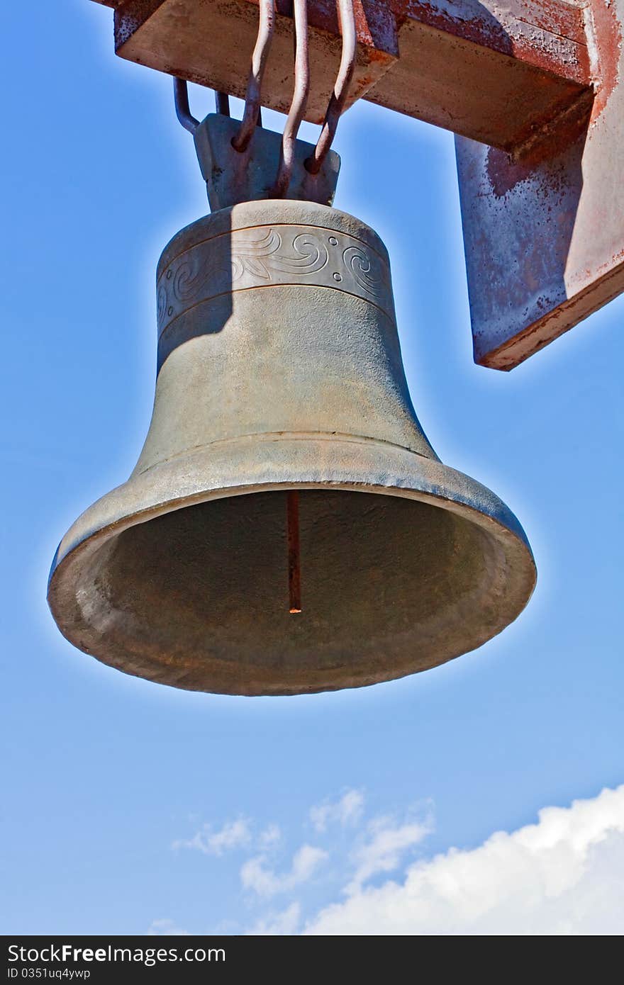 Weathered cast-iron bell against blue sky