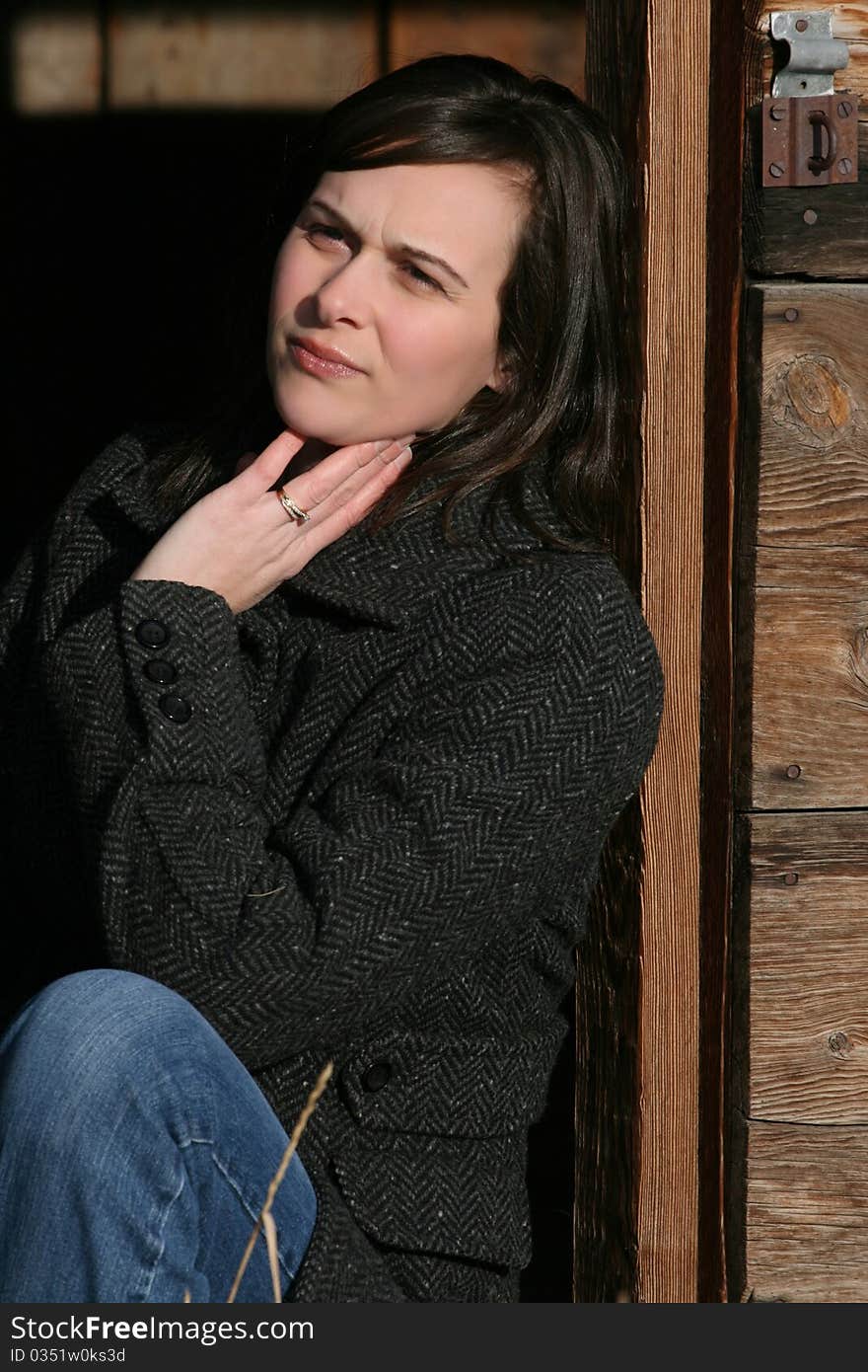 Beautiful brunette female leaning against wooden barn