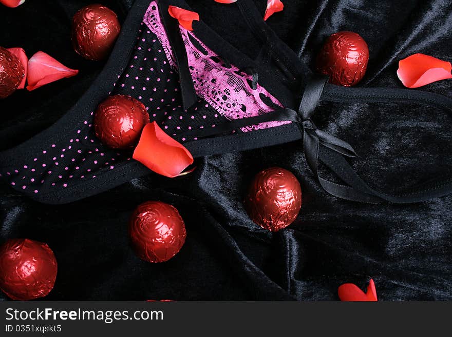 Lace polkadot underwear and chocolates with rose petals. Lace polkadot underwear and chocolates with rose petals