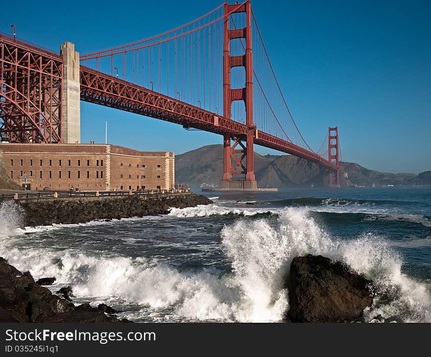 Golden Gate Bridge with large wave crashing.