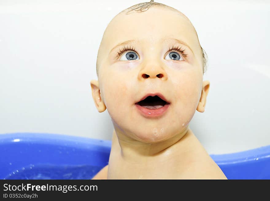 Excited blue-eyed baby boy taking a bath