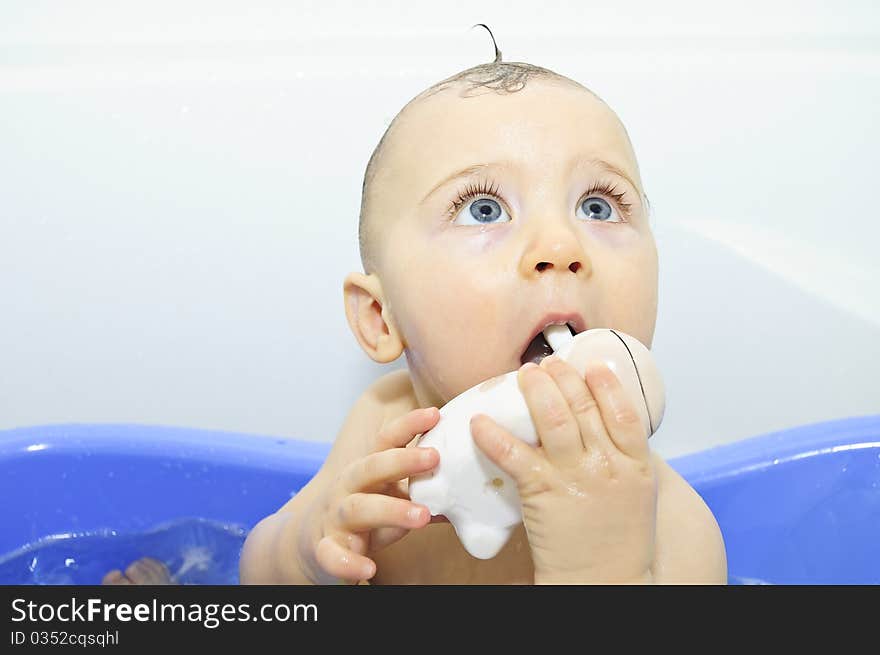 Excited blue-eyed baby boy taking a bath