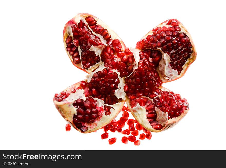 The pomegranate broken on some parts with the grains scattered nearby (on a white background). The pomegranate broken on some parts with the grains scattered nearby (on a white background)