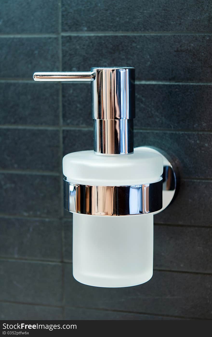 An isolated stainless steel metal and glass soap dispenser.