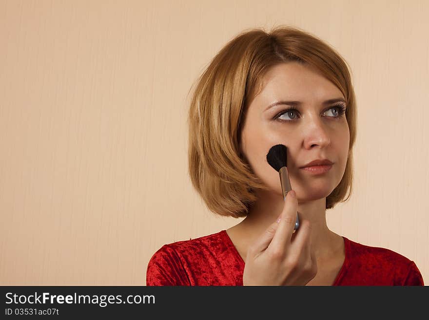 Portrait of the girl in a red with a brush for make-up. Portrait of the girl in a red with a brush for make-up