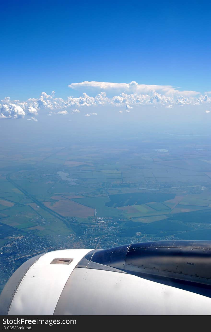 View of aircraft engine in flight, sky and ground