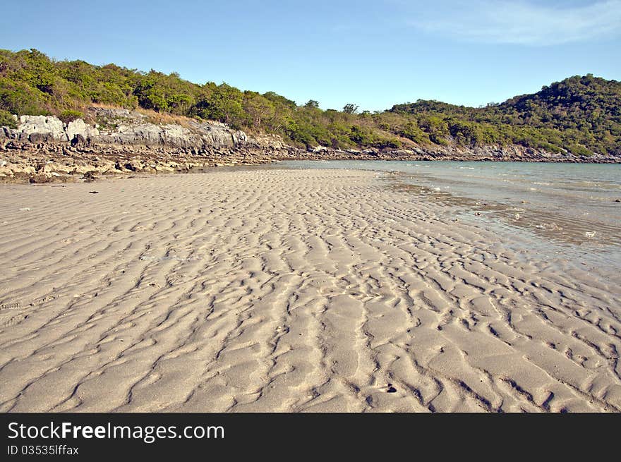 Sand strip by the sea with blue sky