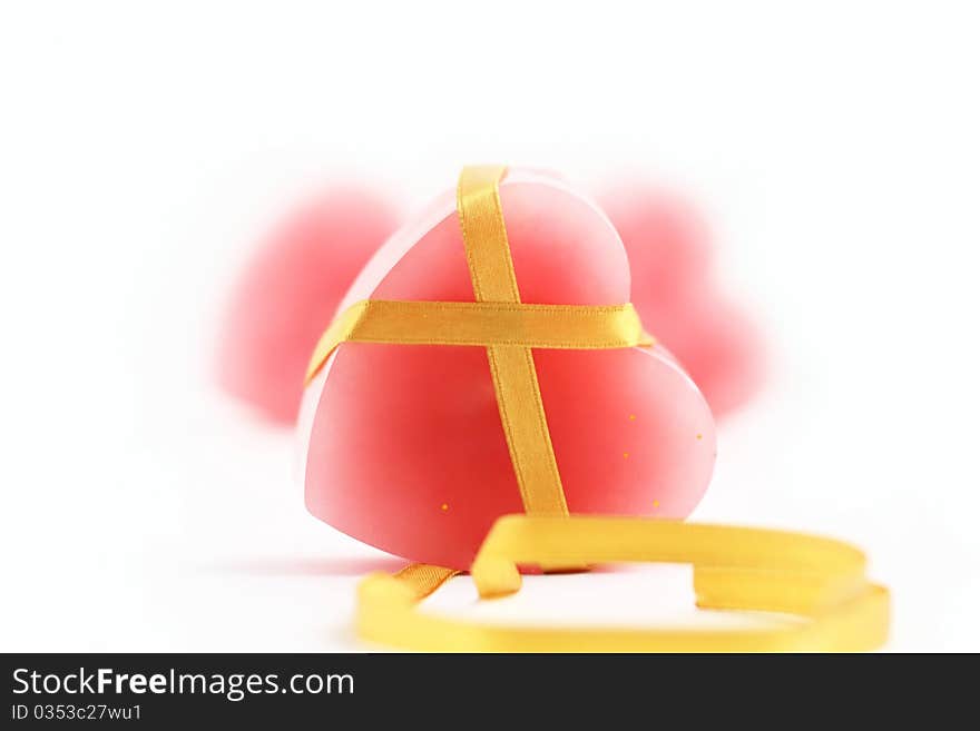 It is photo of pink candle in the form of heart with long gold ribbon against the background two other pink-heart candles. It is photo of pink candle in the form of heart with long gold ribbon against the background two other pink-heart candles.