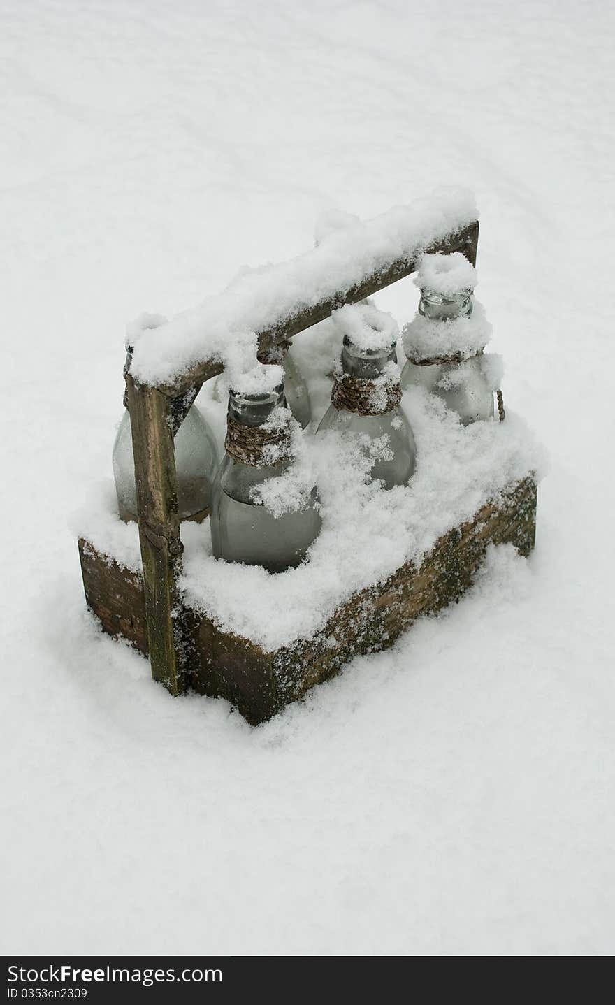 Bottles in a wooden tray in the snow