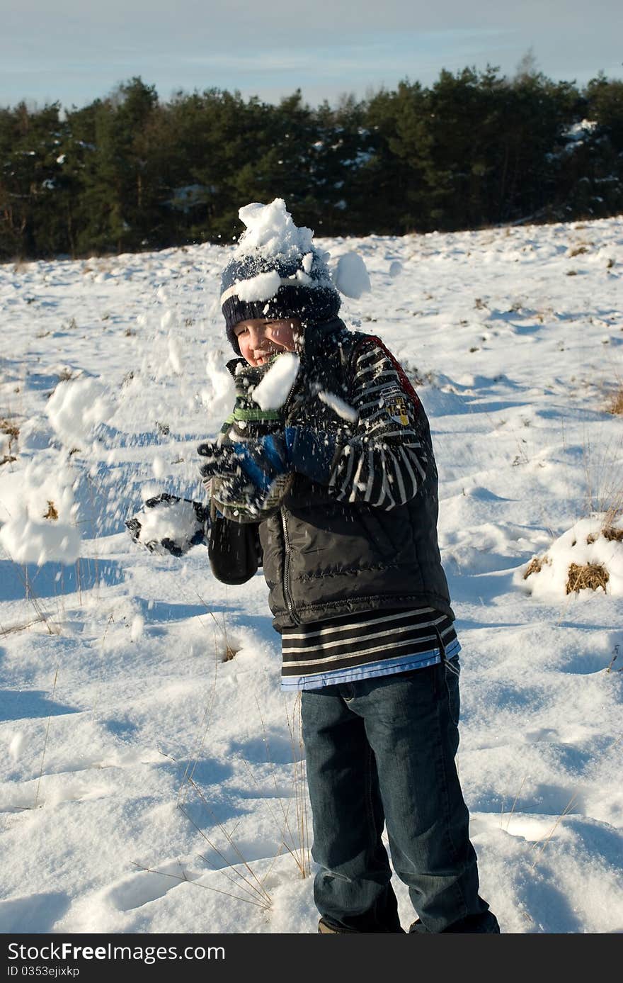 Little boy having fun in snow with snowballs