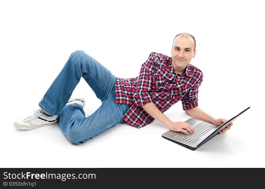 Happy young man surfing on laptop, lying down. Isolated on white background