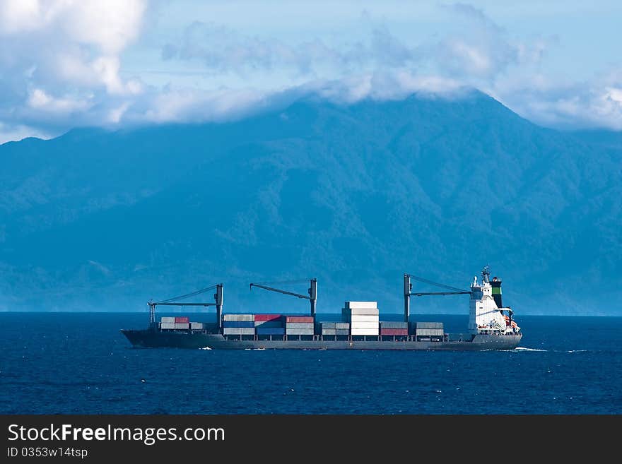 Cargo container ship in Pacific with mountains in background. Cargo container ship in Pacific with mountains in background.