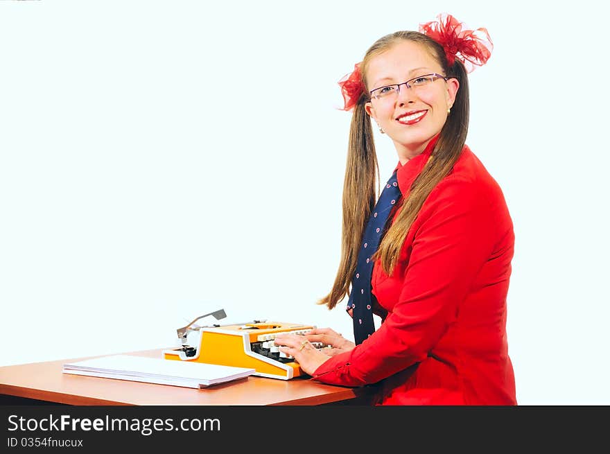 A girl sits at a desk and typing on a typewriter, by her side lay a sheets of white paper. A girl sits at a desk and typing on a typewriter, by her side lay a sheets of white paper