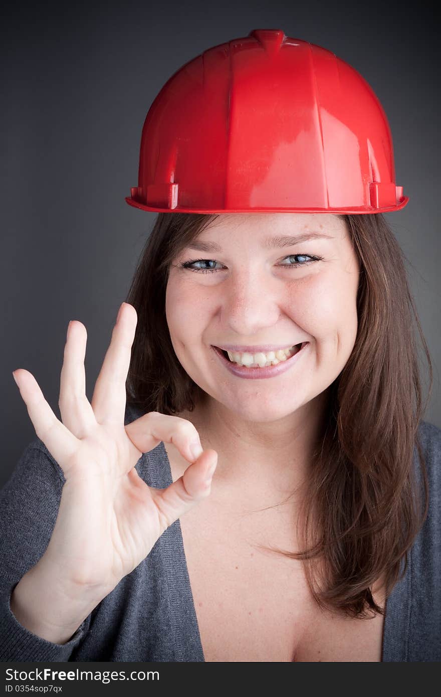 Young Engineer Woman doing the ok sign, wearing red safety hat