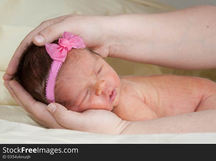 A cute 1 week old baby being held in her Mom's hands. A cute 1 week old baby being held in her Mom's hands.