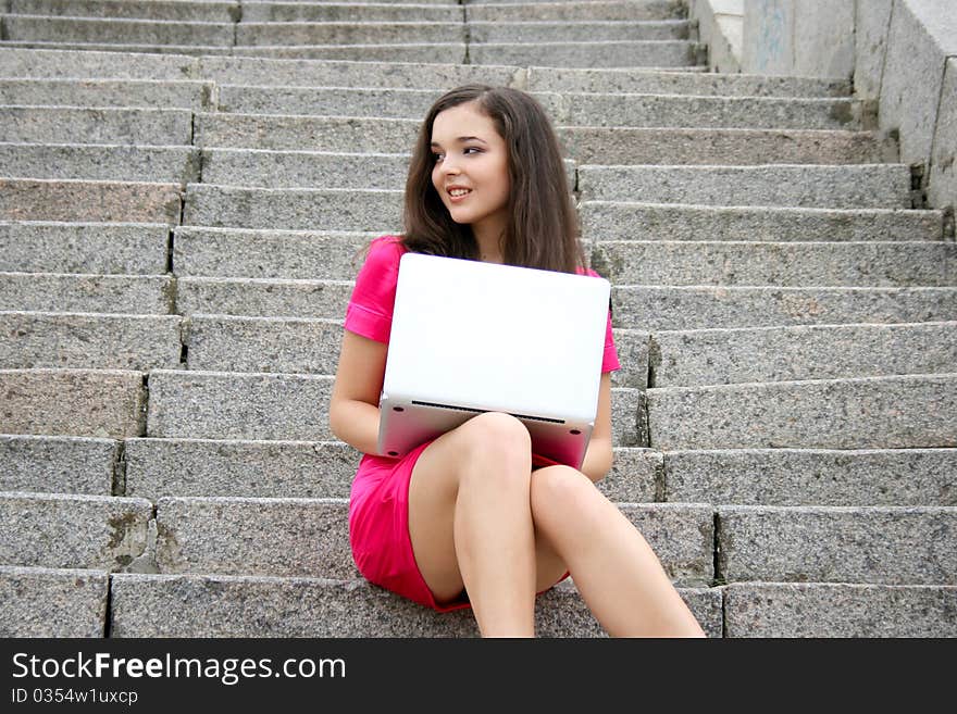 Young caucasian student women with laptop  in pink dress