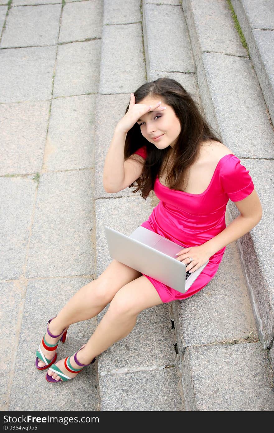 Young caucasian student women with laptop in pink dress