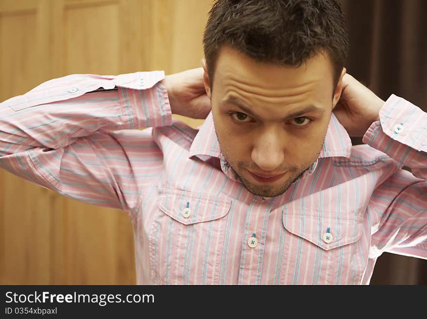 Young man is buttoning pink shirt in the morning. Young man is buttoning pink shirt in the morning.