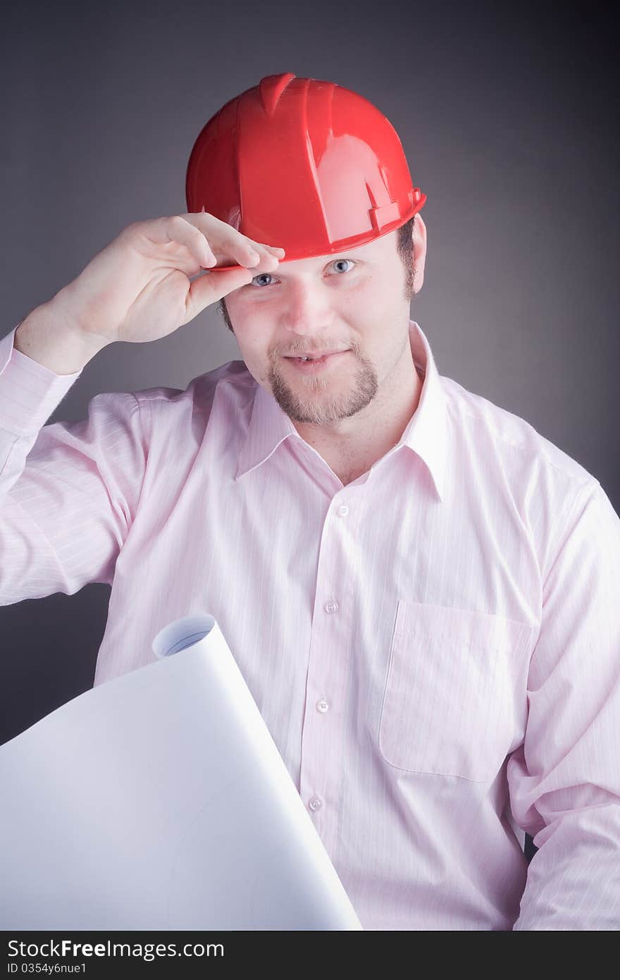 Young Engineer with blueprints raises his hat, wearing safety hat