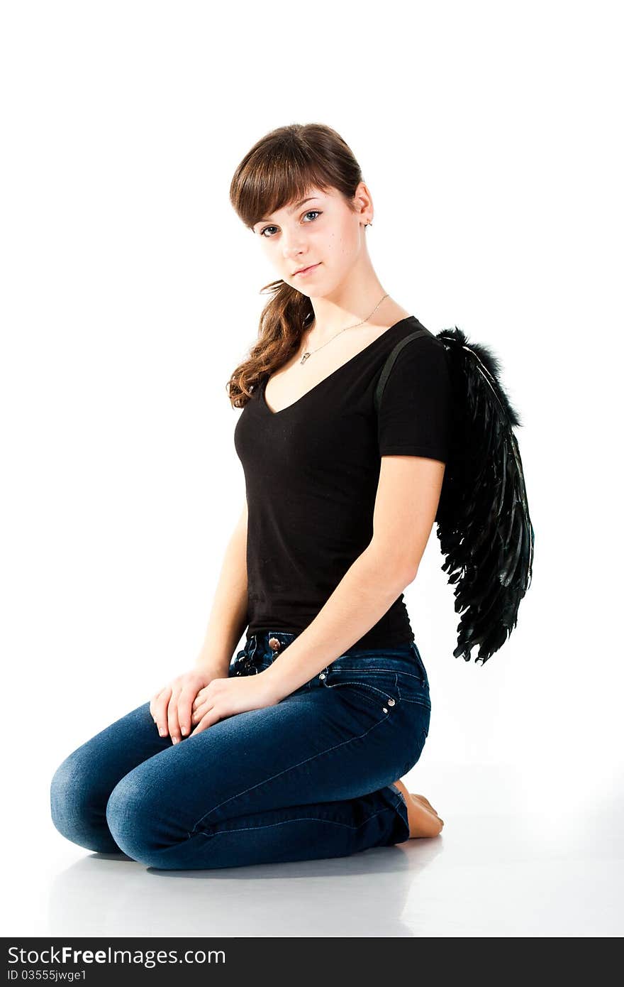 Beautiful girl sitting in black wings isolated on white