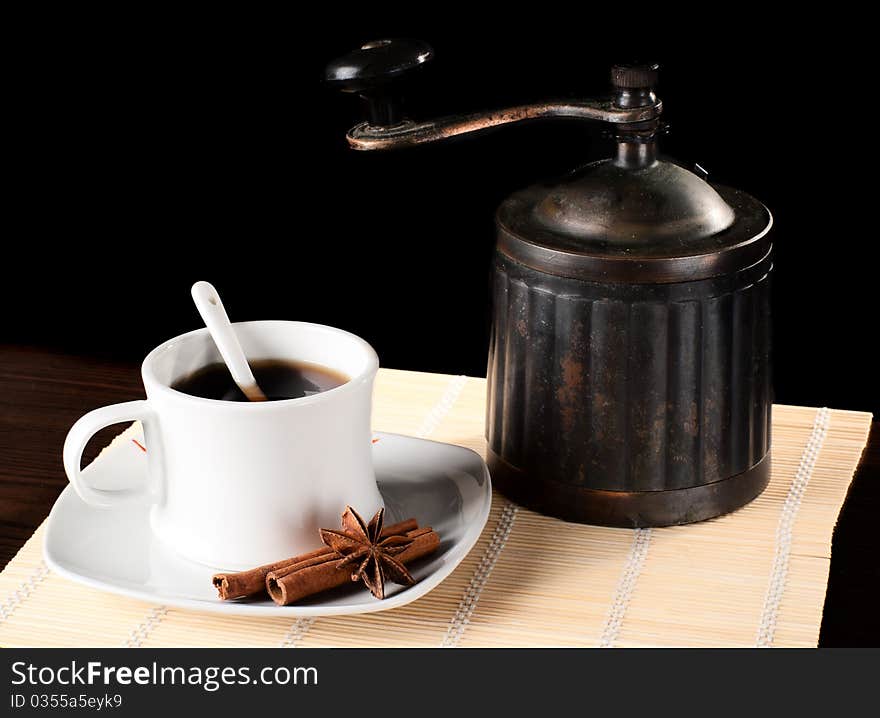 A cup of coffee with an old grinder and cinnamon. Studio shot. A cup of coffee with an old grinder and cinnamon. Studio shot.