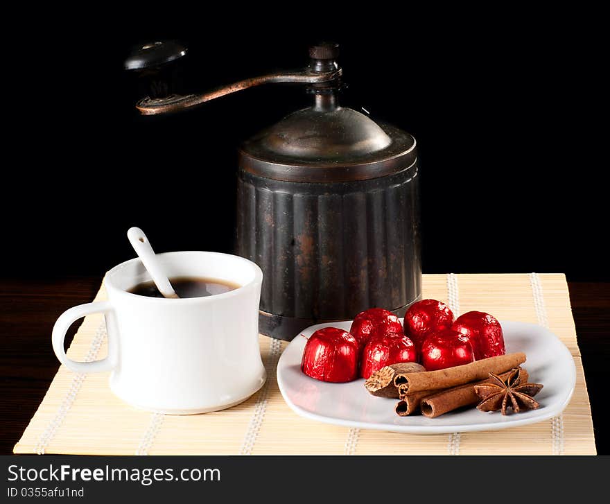 A cup of coffee with grinder and sweets.