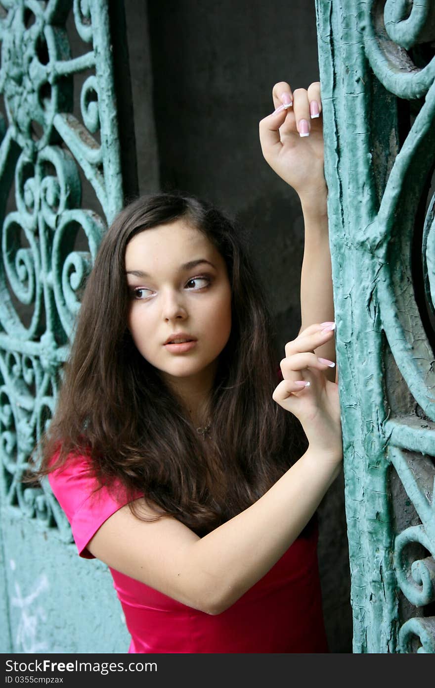 Young caucasian woman in pink dress near the gates. Young caucasian woman in pink dress near the gates