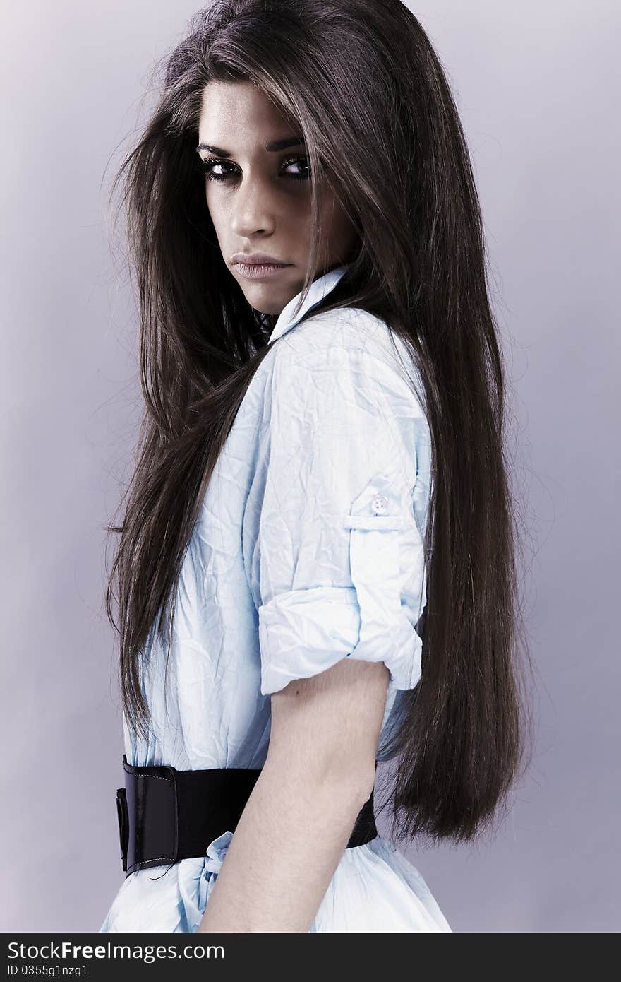 Portrait of trendy young woman in funky blue shirt pose against gray background