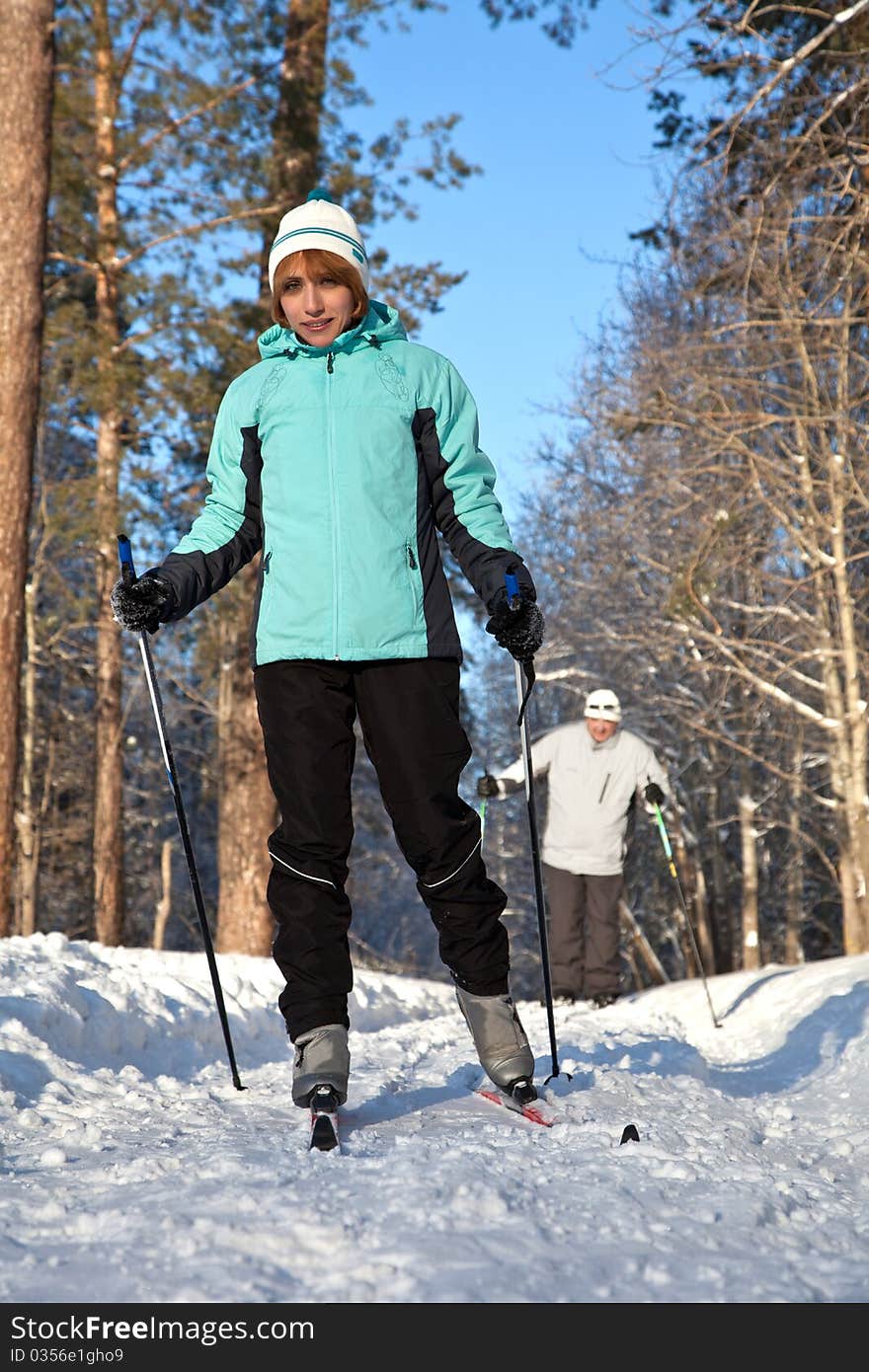 Man and woman walking on ski in winter forest