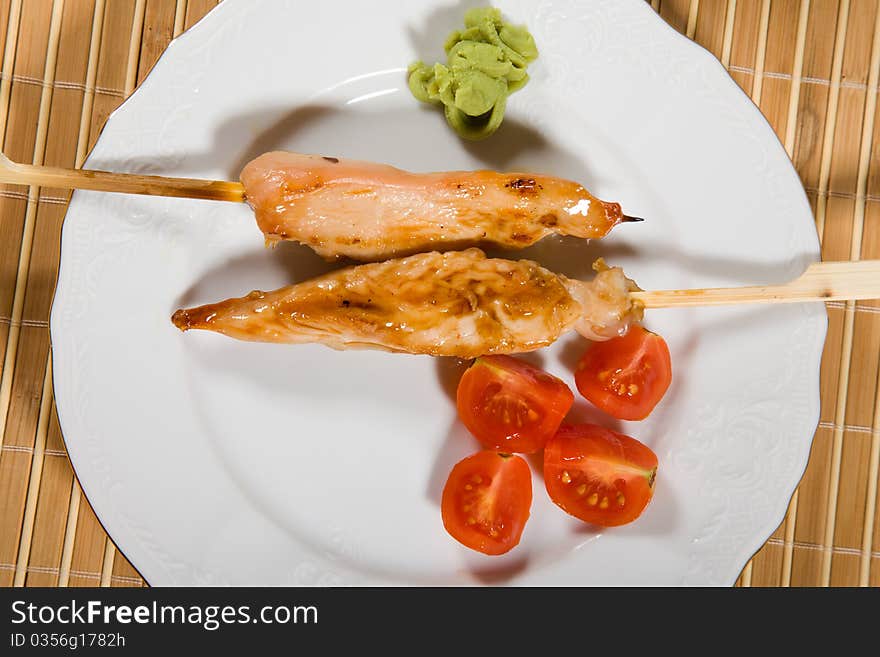 Hot barbecued chicken fillet as closeup on a white plate