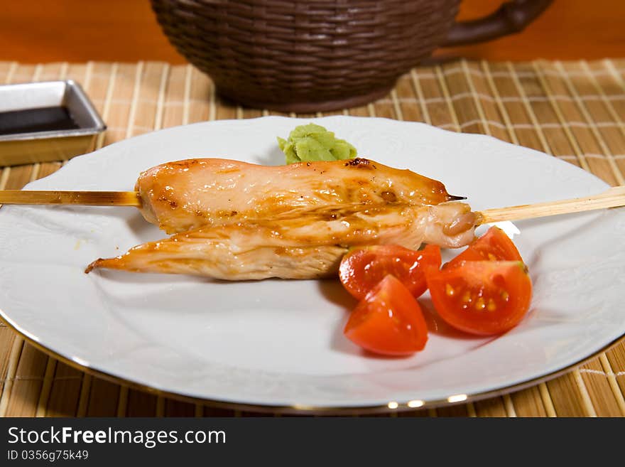 Hot barbecued chicken fillet as closeup on a white plate