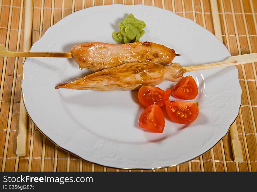 Hot barbecued chicken fillet as closeup on a white plate