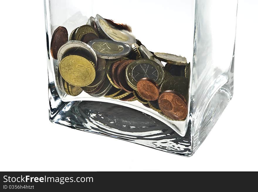 Euro coins in a glass container on white