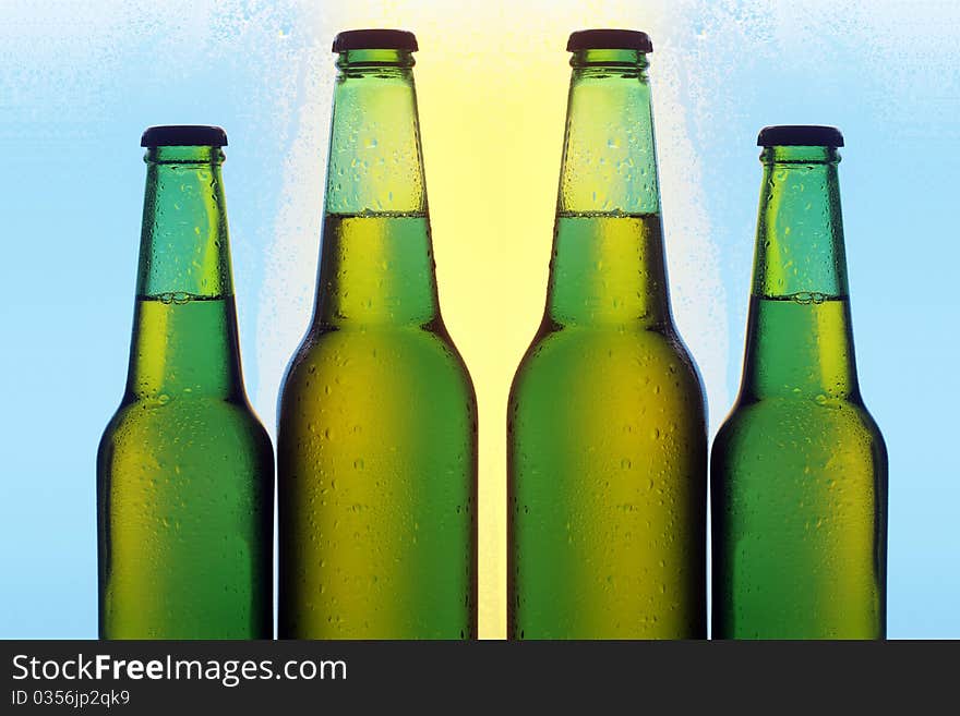 Four bottles of beer with cold droplets