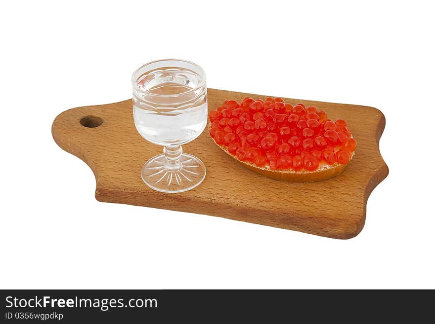 Bread with red caviar and glass of vodka on wooden plank