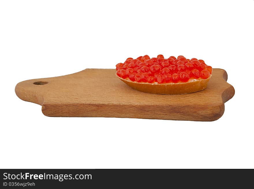 Bread and red caviar on wooden plank