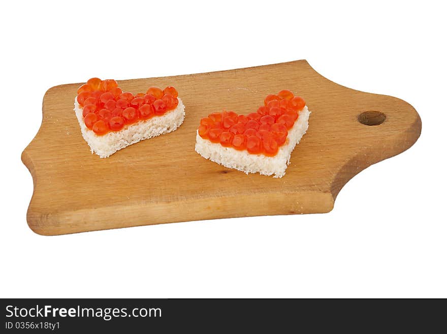 Two pieces of bread in the form of a heart with red caviar on wooden plank on white background. Two pieces of bread in the form of a heart with red caviar on wooden plank on white background