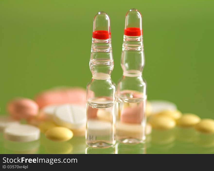 Macro ampoule and pills shot on green background