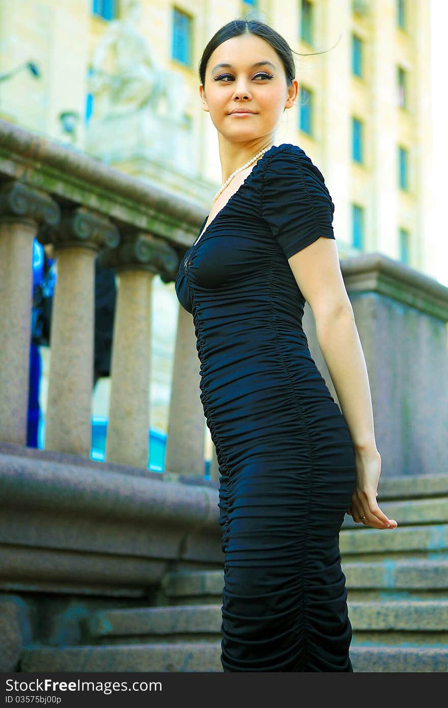 Beautiful Asian girl in a black dress and high heels sitting on the stairs. Beautiful Asian girl in a black dress and high heels sitting on the stairs