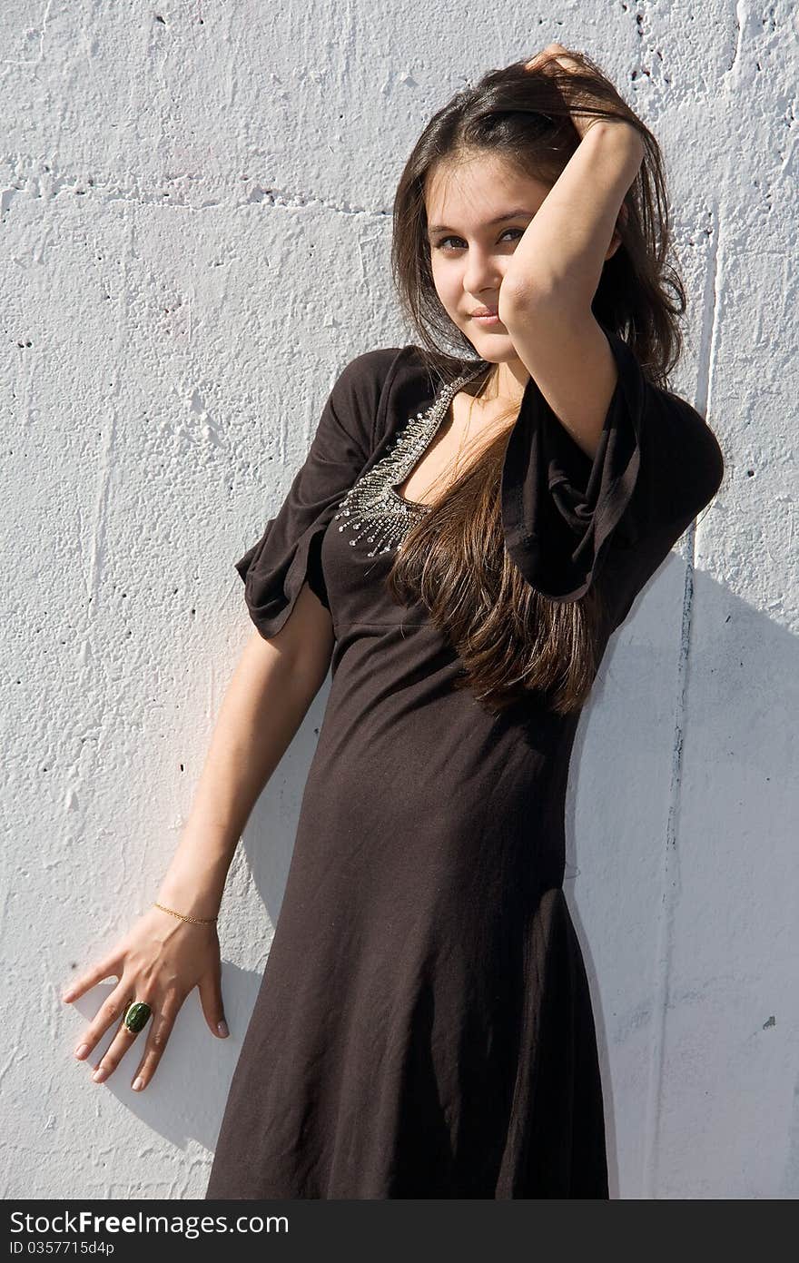 Beautiful Asian girl in brown dress on a background of white stone wall. Beautiful Asian girl in brown dress on a background of white stone wall