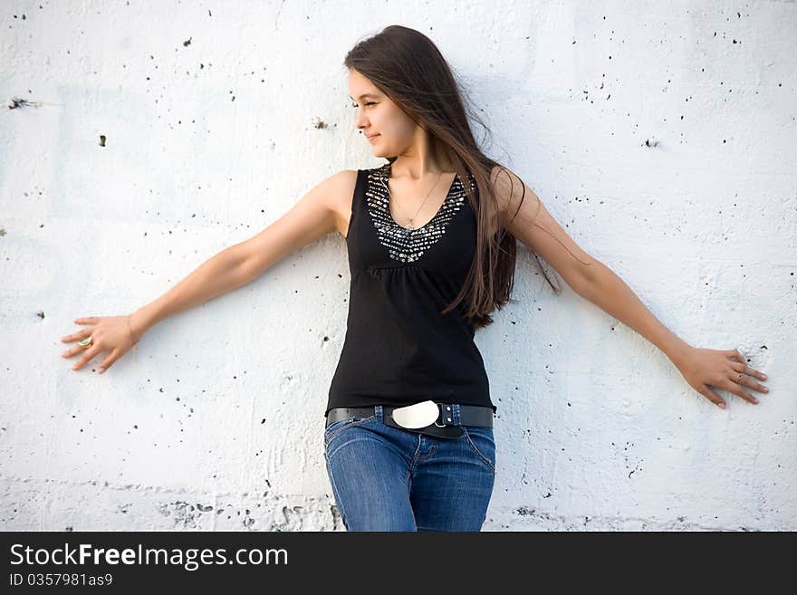 Beautiful Asian girl in jeans on a background of white stone wall