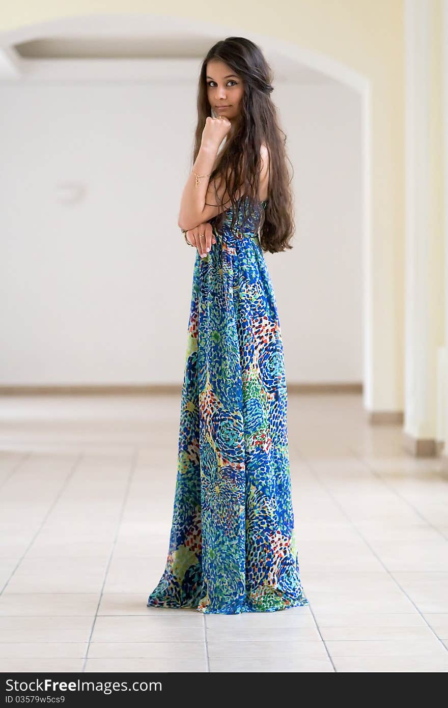 Beautiful Asian girl in a long floral dress standing in a white corridor