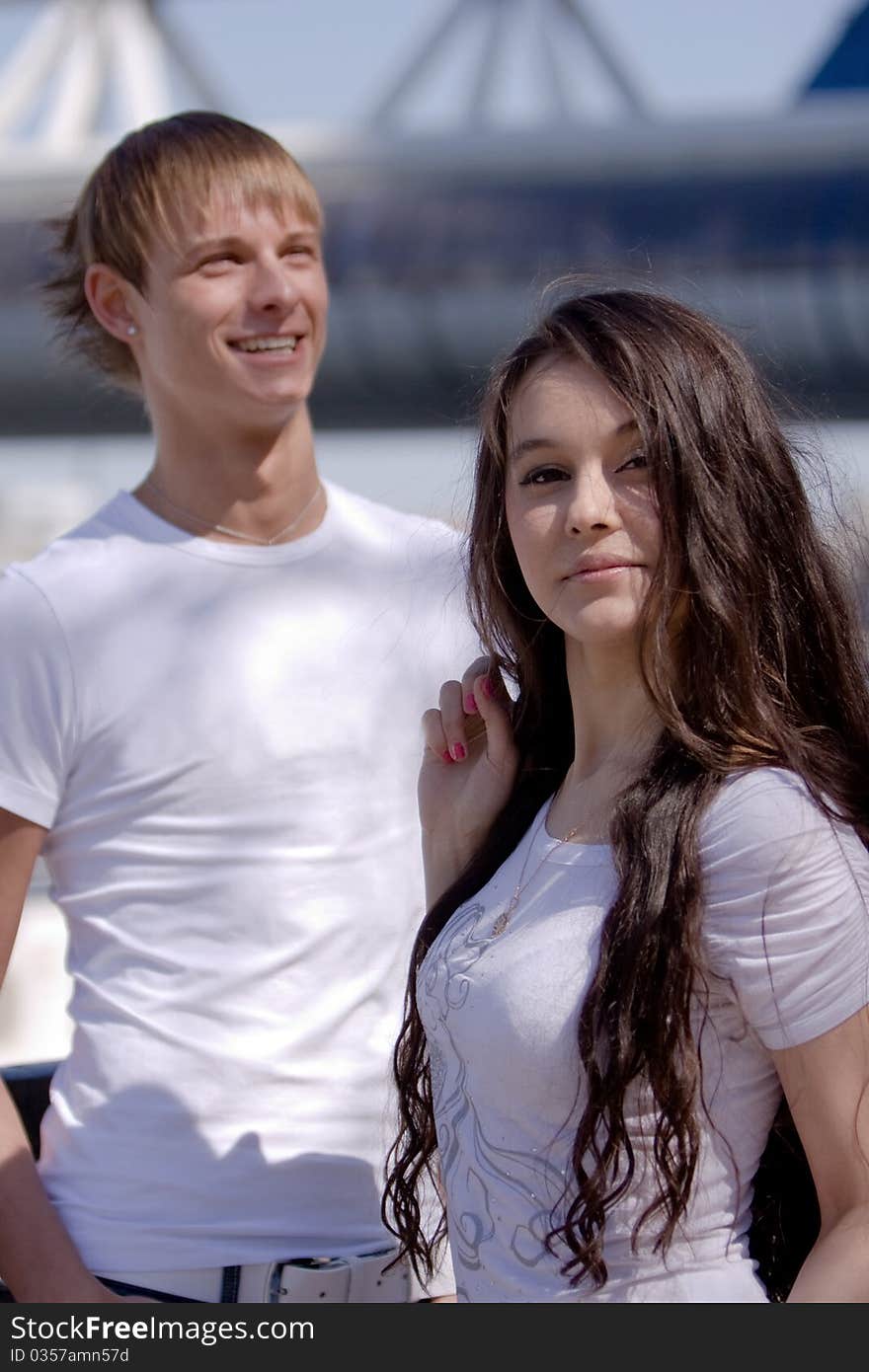 Two fashionable and trendy teenagers against the blue sky and skyscrapers (modern buildings)