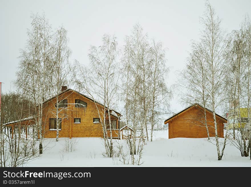 Suburb, cottage or chalet of stained wood, luxury house, residential structure, residential district, construction timber, prefabricated buildings with double glazing, winter trees, snow, white and brown. Suburb, cottage or chalet of stained wood, luxury house, residential structure, residential district, construction timber, prefabricated buildings with double glazing, winter trees, snow, white and brown