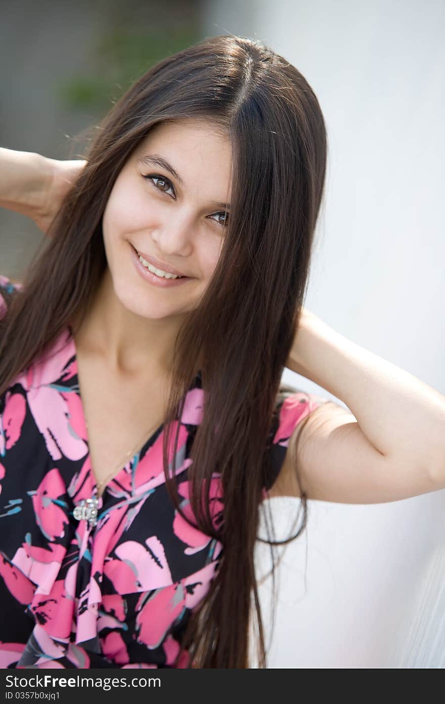 Beautiful Asian girl in pink dress on a background of white stone wall