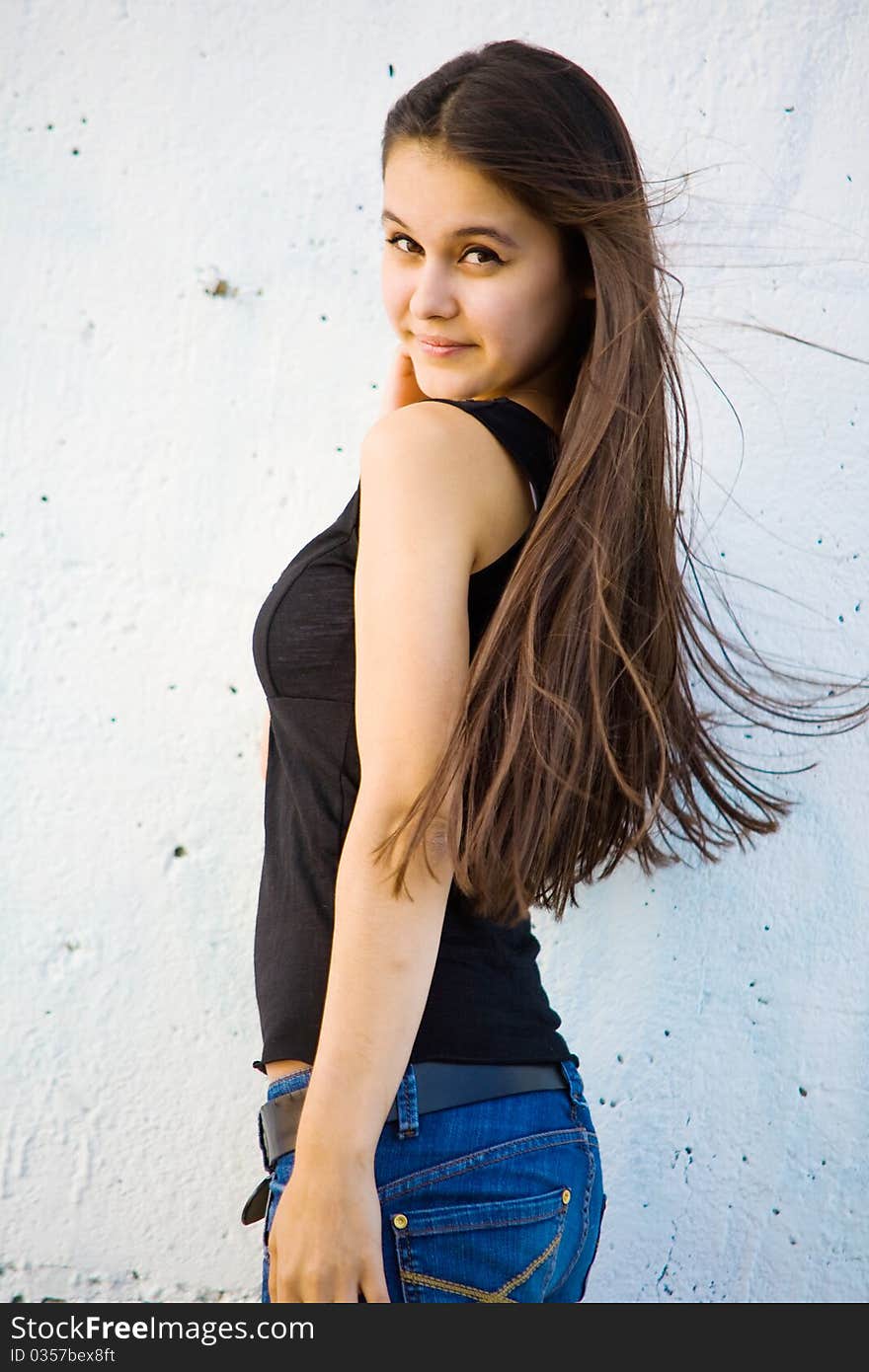 Beautiful Asian girl in jeans on a background of white stone wall